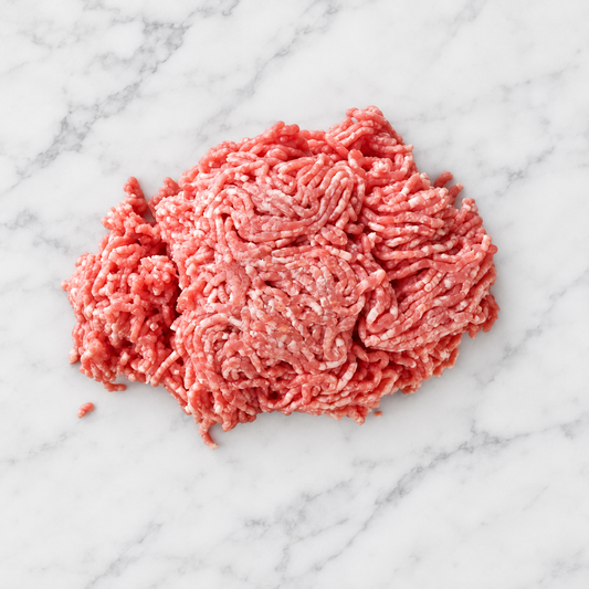 Raw ground Mangalitsa pork on white marble; AI-assisted background edit of owned product photo